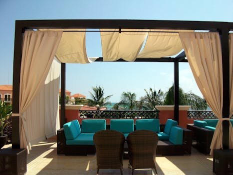 Elegant outdoor seating area on a sunlit rooftop overlooking the ocean.